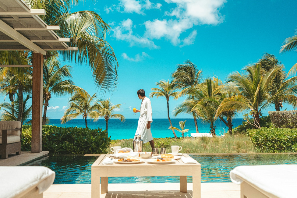 Man looking at a beach while walking past a pool.