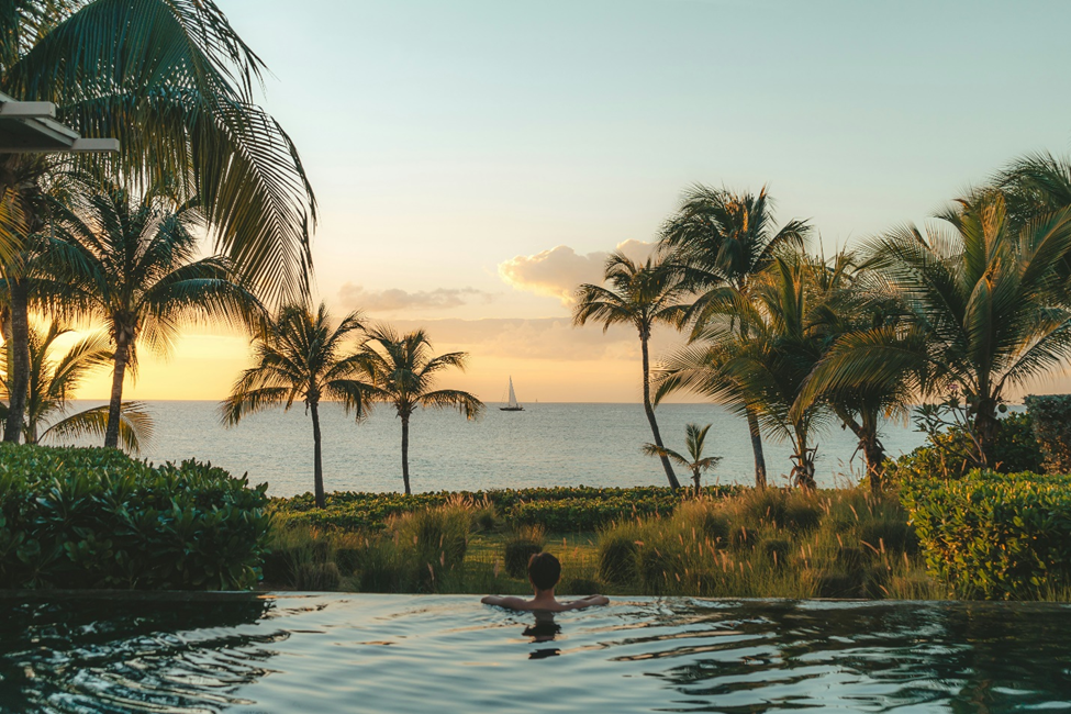 Man in pool looking at the ocean.